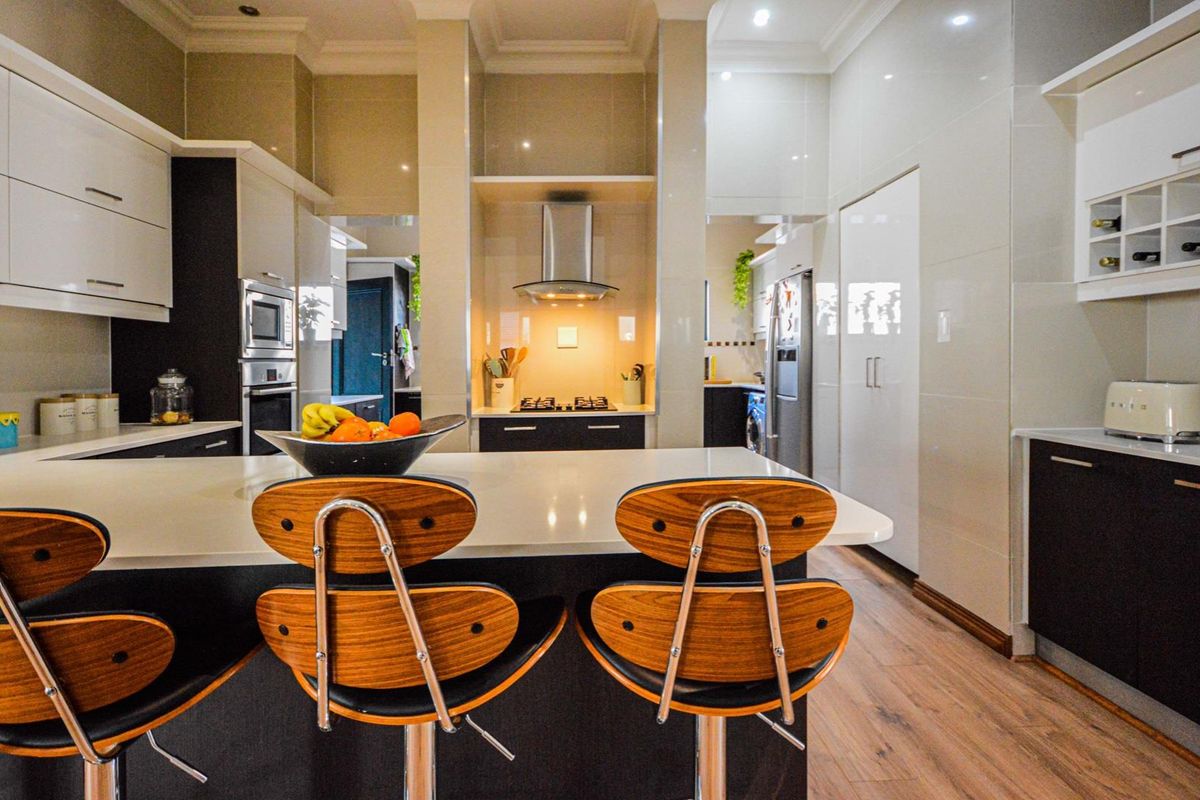 Modern kitchen featuring high-gloss cabinetry, quartz countertops, a central island, and integrated appliances including a gas hob and built-in oven.