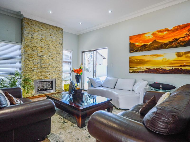 Spacious living room featuring a prominent stone-clad fireplace, recessed downlighting, and sliding glass doors providing access to the outdoor area.