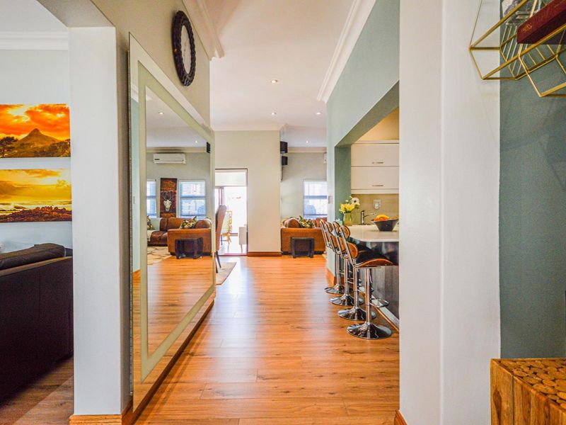 An open-plan living area featuring laminate flooring, recessed lighting, and a kitchen breakfast bar, creating a seamless flow between the kitchen and living spaces.