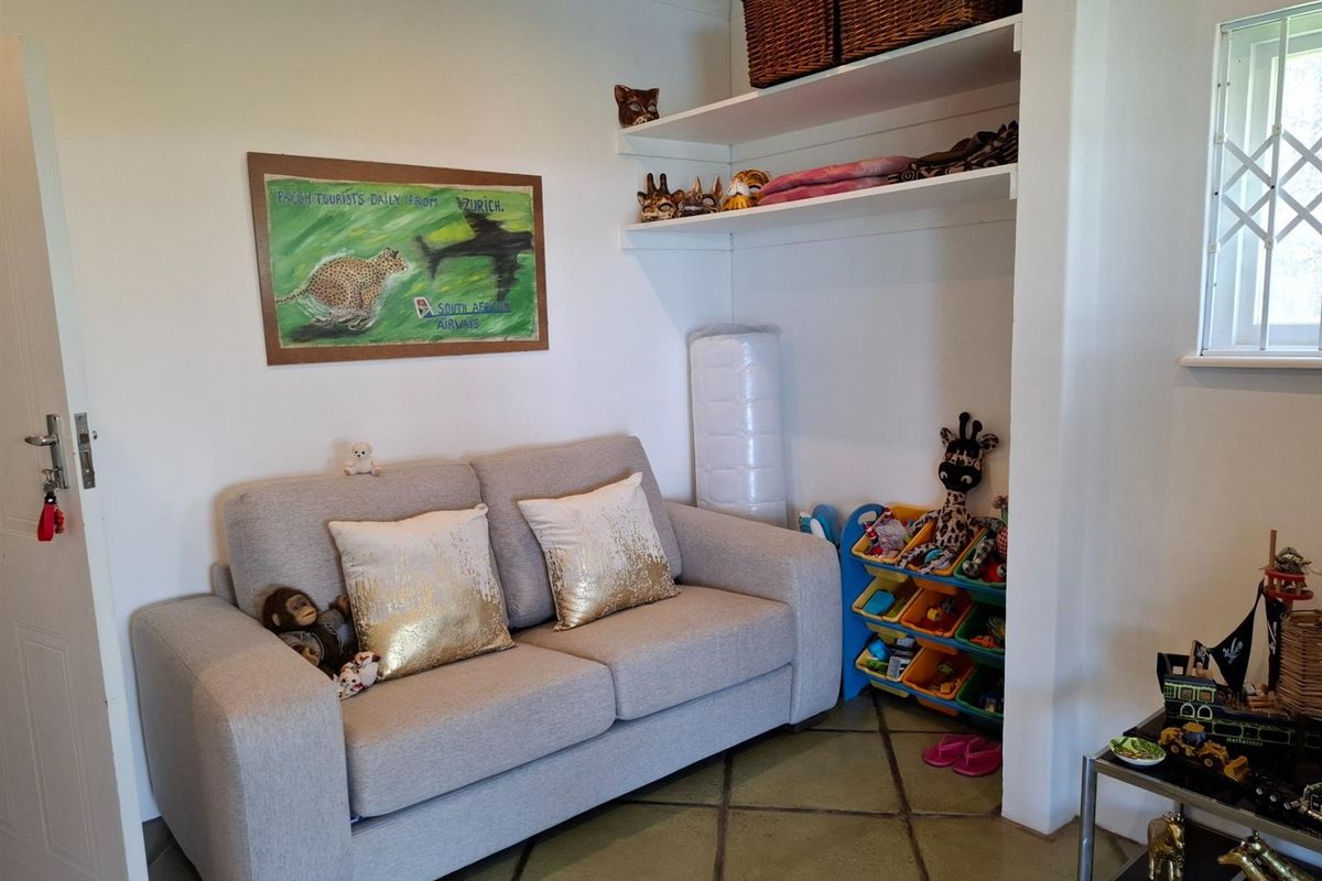 A living area featuring tiled flooring and built-in shelving, providing a functional space with potential for updated styling.