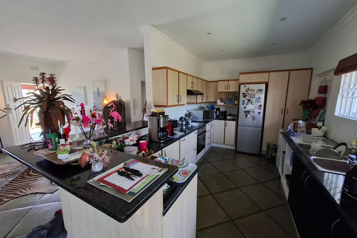 A functional kitchen featuring granite countertops, ample built-in cabinetry, and integrated appliances, flowing into an open-plan living area.