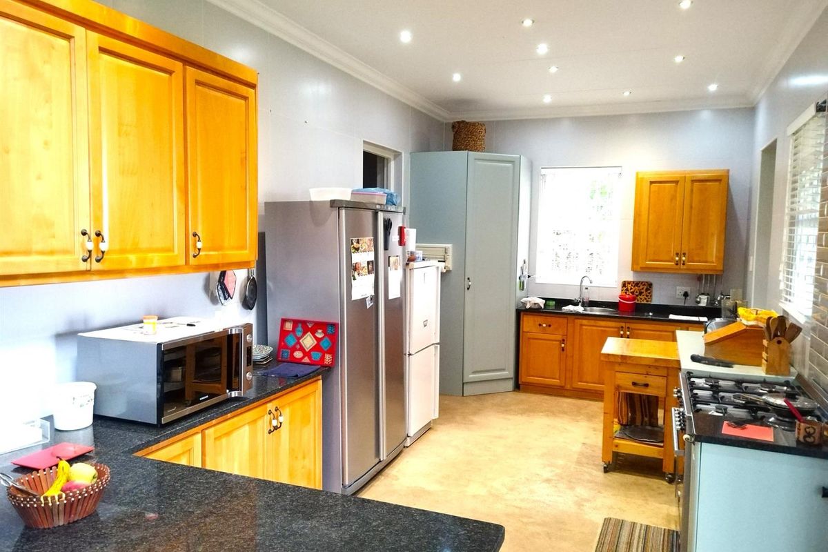 A spacious kitchen featuring wooden cabinetry, dark granite countertops, recessed ceiling lighting, and a functional layout with ample storage and workspace.