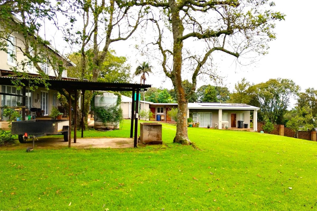 Spacious rear garden featuring a large lawn, mature trees, a covered patio area, and a water storage tank.