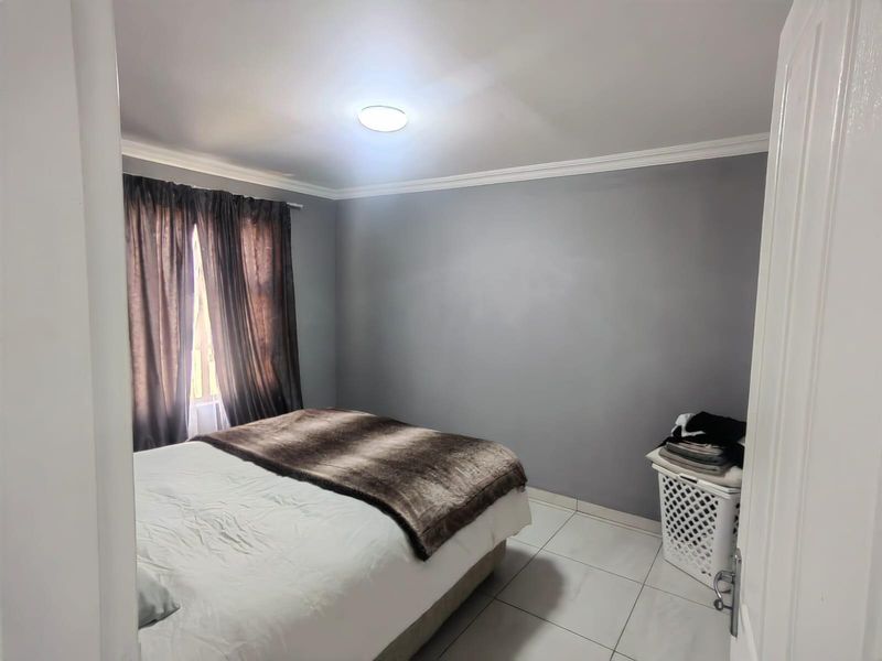 A bedroom featuring tiled flooring, crown molding, and a central ceiling light fixture.