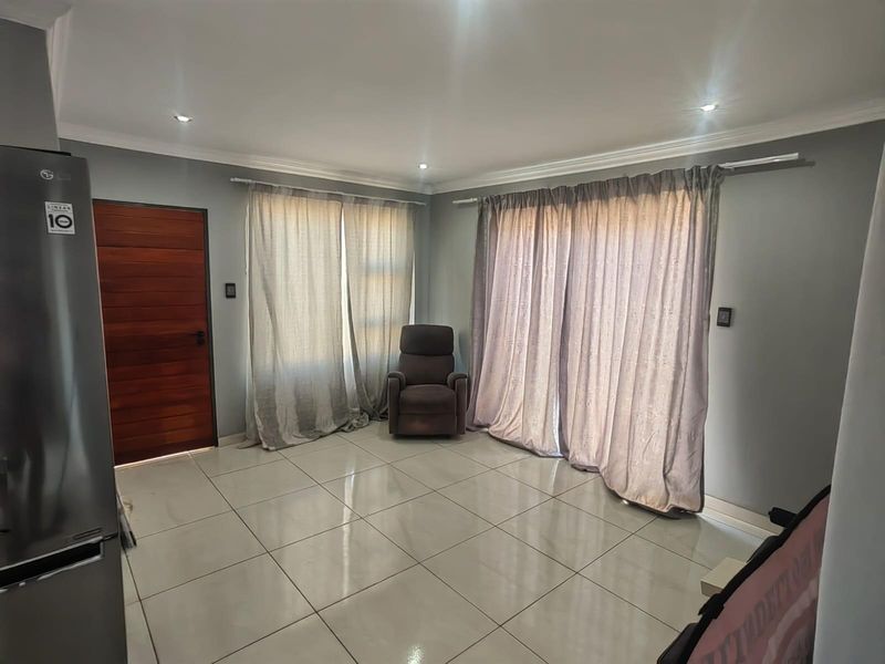 A bright living area featuring large format floor tiles, recessed ceiling lighting, and sliding door access to the exterior.