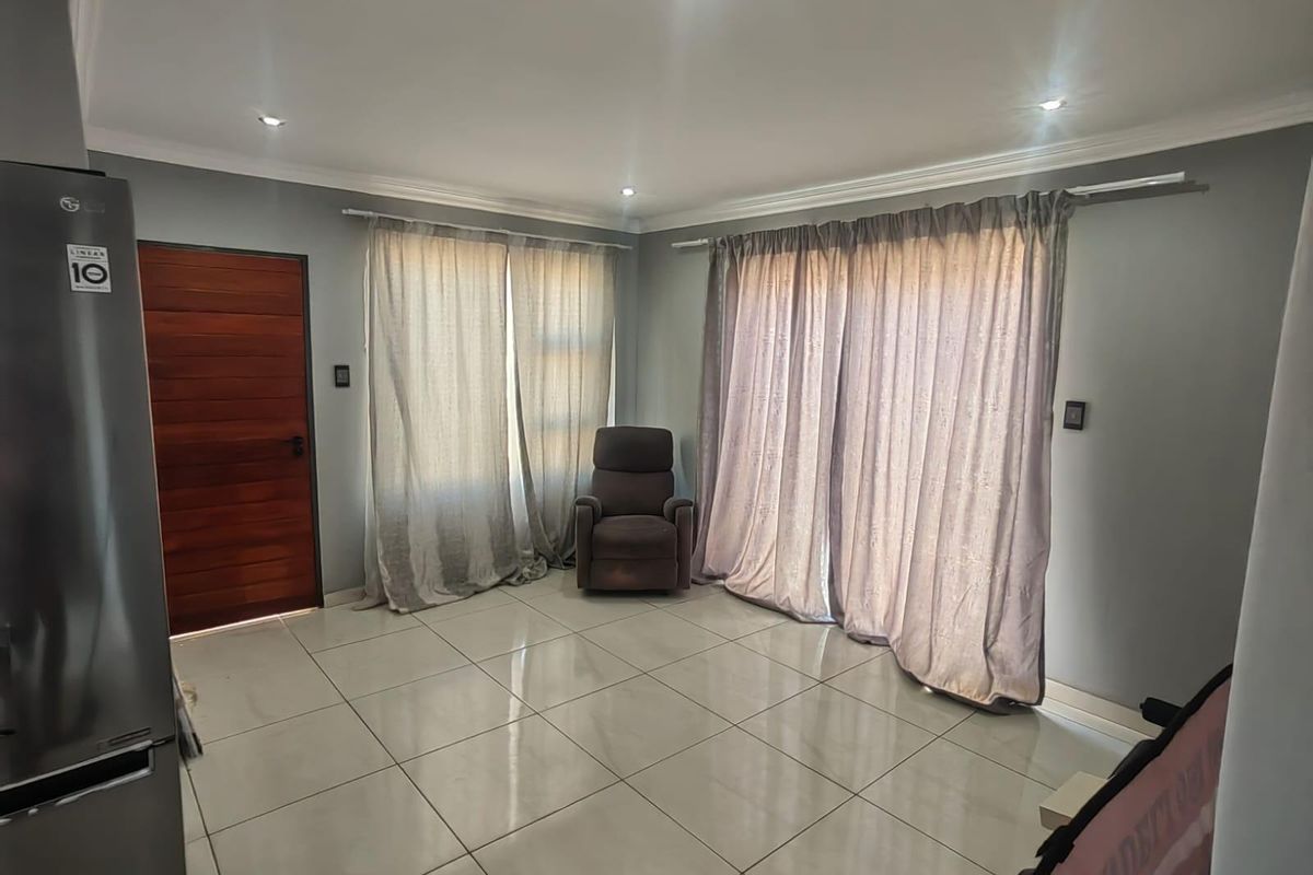 A bright living area featuring large format floor tiles, recessed ceiling lighting, and sliding door access to the exterior.