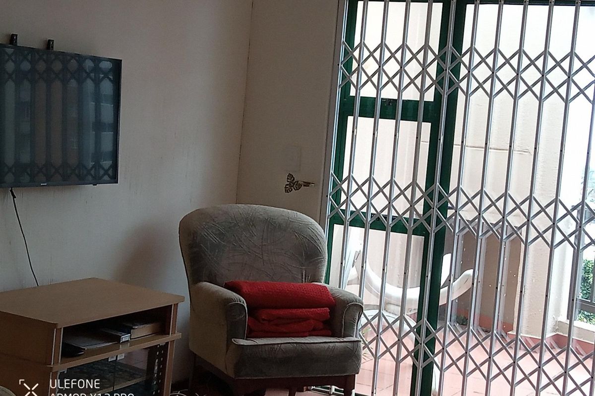 Living room area featuring a sliding door with a fitted security gate providing access to an outdoor space.