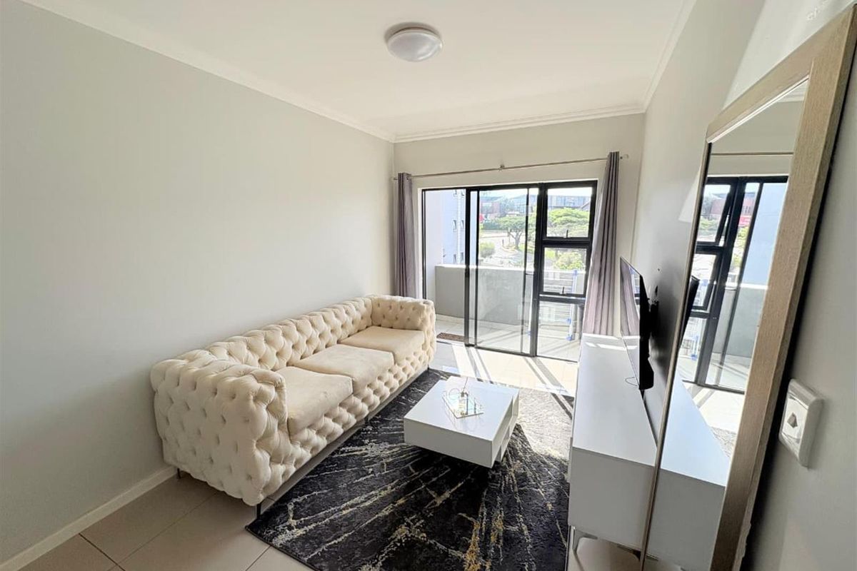 A bright living room featuring tiled flooring and a large sliding glass door that provides access to an outdoor balcony area.