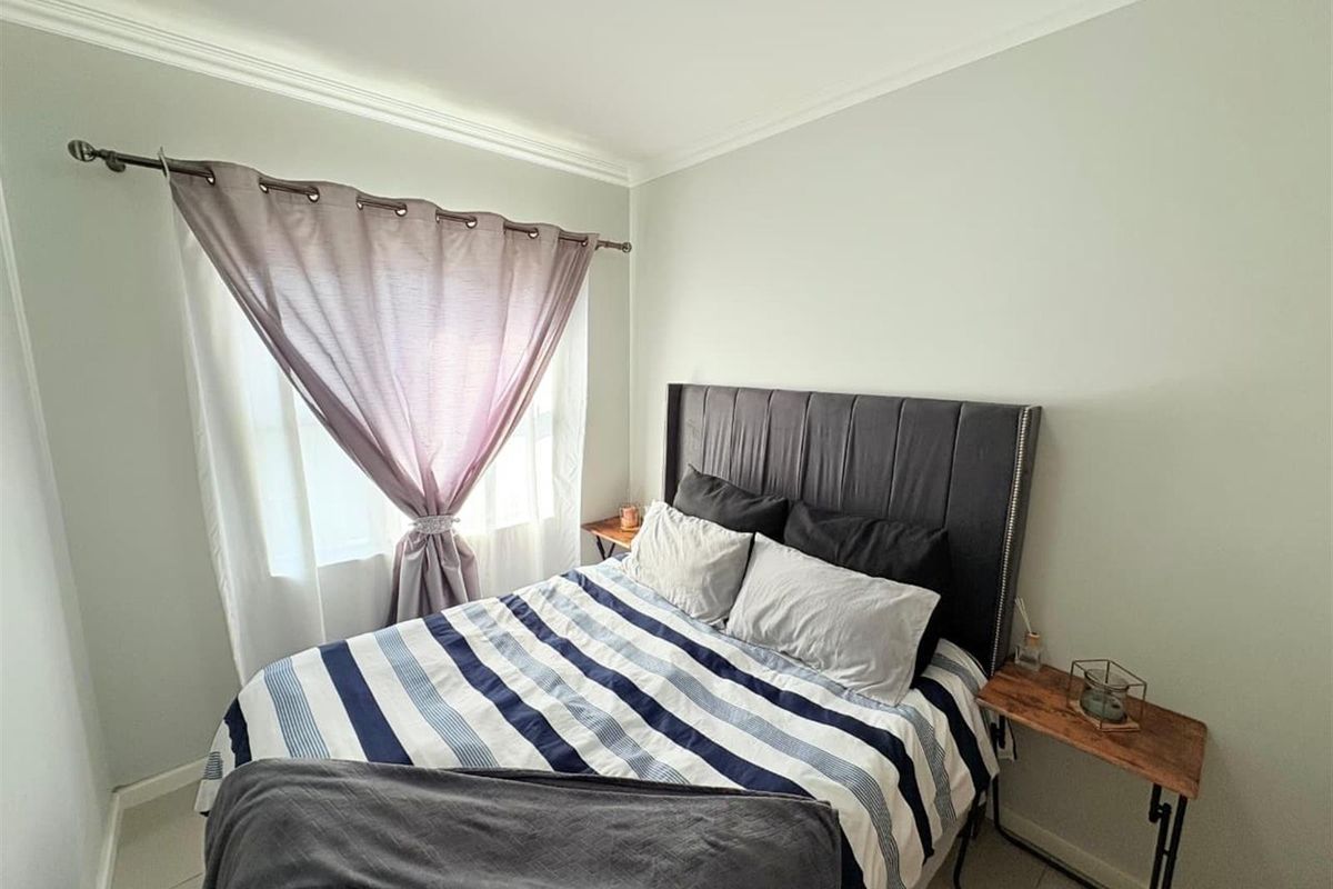 A well-maintained bedroom featuring neutral wall tones, coving, and tiled flooring, providing a clean and comfortable living space.