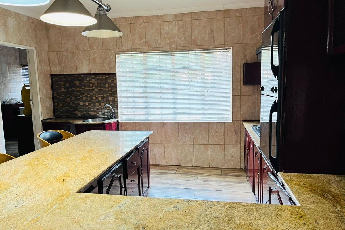 A functional kitchen featuring granite countertops, built-in cabinetry, integrated oven, and tiled wall finishes with a breakfast bar area.