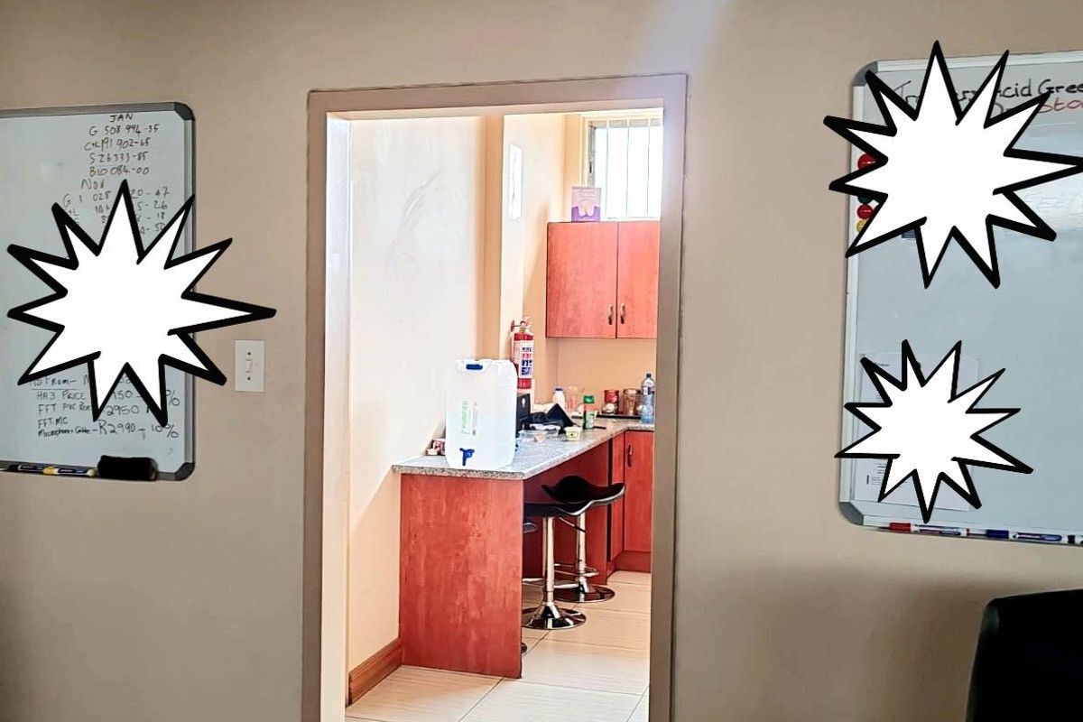 A view through a doorway into a small kitchenette area featuring wooden cabinetry, a stone-look countertop, and tiled flooring.