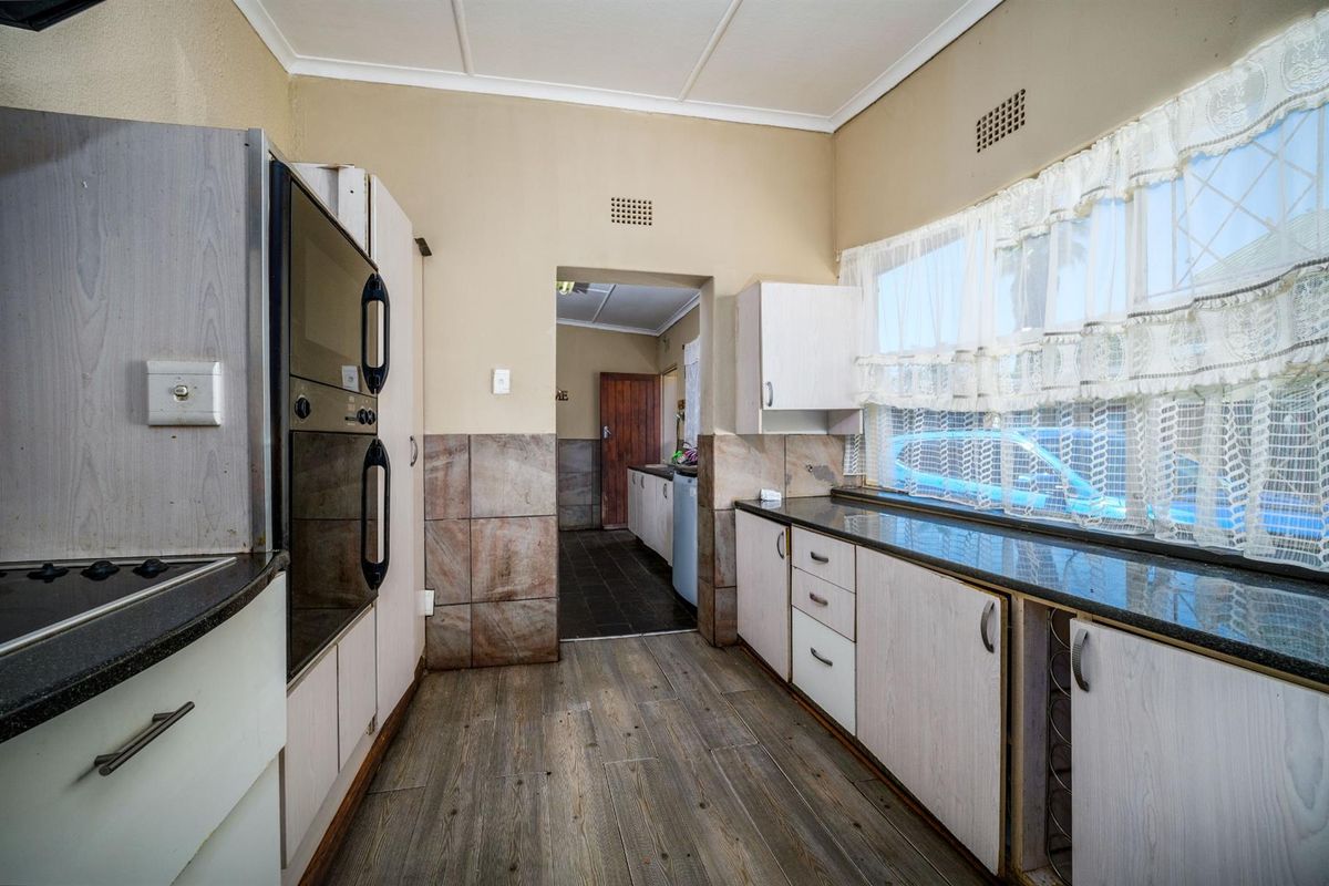 A functional kitchen featuring built-in cabinetry, dark stone countertops, integrated oven, and a pass-through leading to an adjacent utility area.