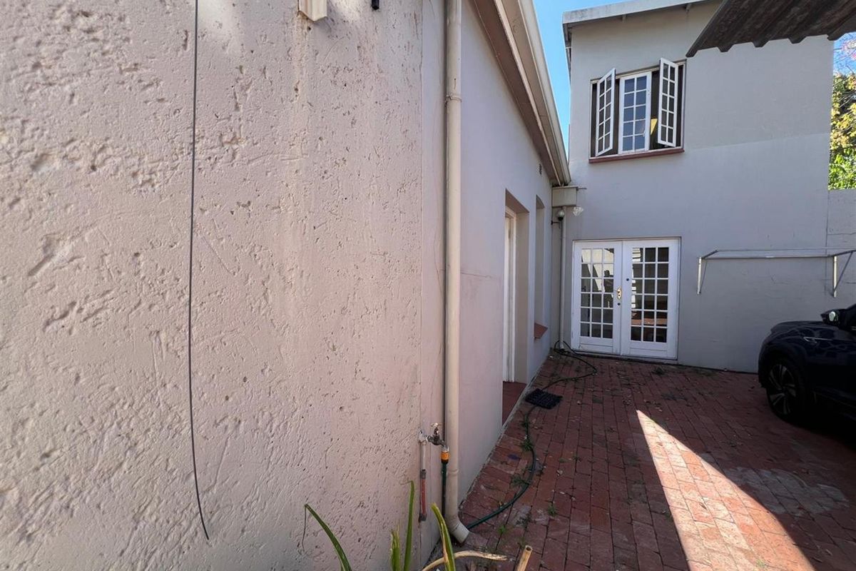 Rear exterior view showing brick paved courtyard area with french doors and casement windows.