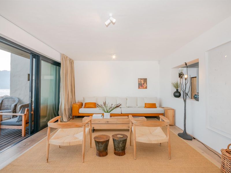 Bright and airy living room featuring hardwood flooring, a recessed wall niche, and large sliding glass doors that open onto an outdoor patio area.
