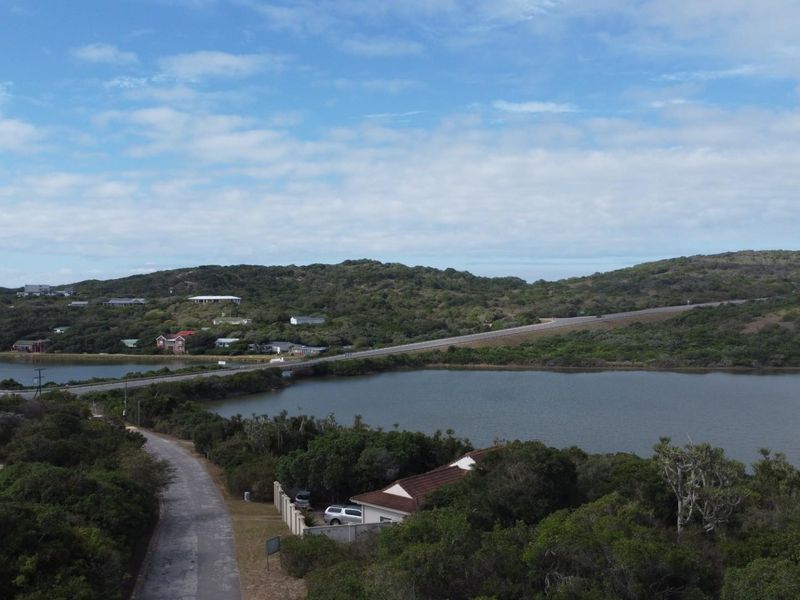 An aerial view of the coastal landscape, showcasing the surrounding natural vegetation, nearby lagoon, and local road infrastructure.