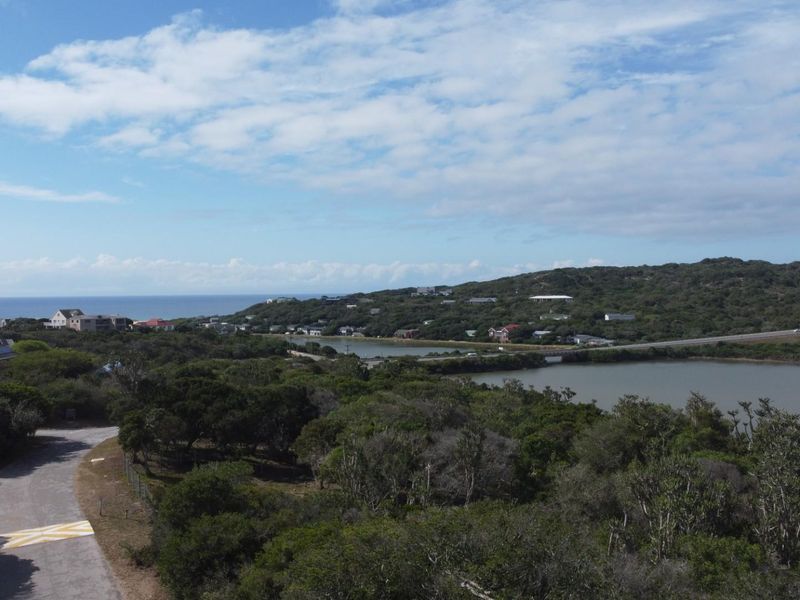 An elevated aerial view of the coastal landscape, featuring natural vegetation, a nearby lagoon, and surrounding residential development.