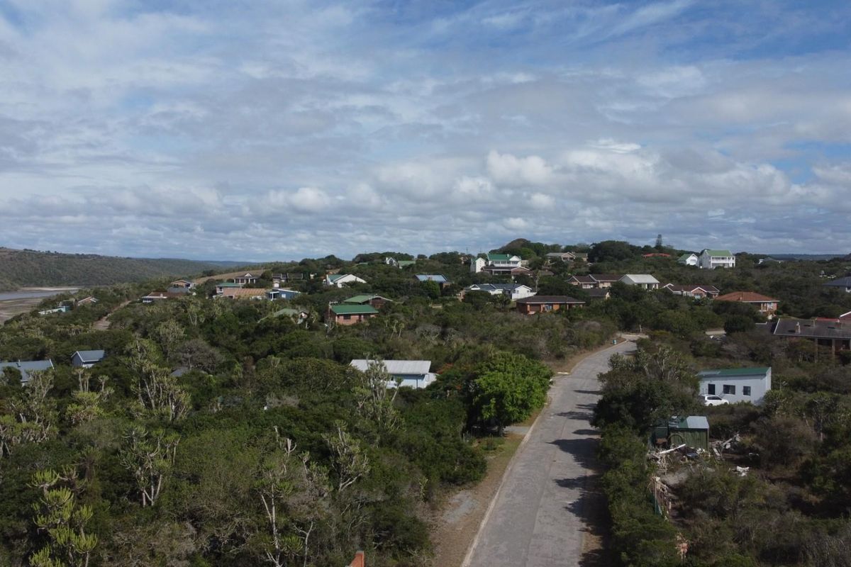 An aerial view of a residential coastal neighborhood featuring paved roads, established vegetation, and surrounding natural landscape.