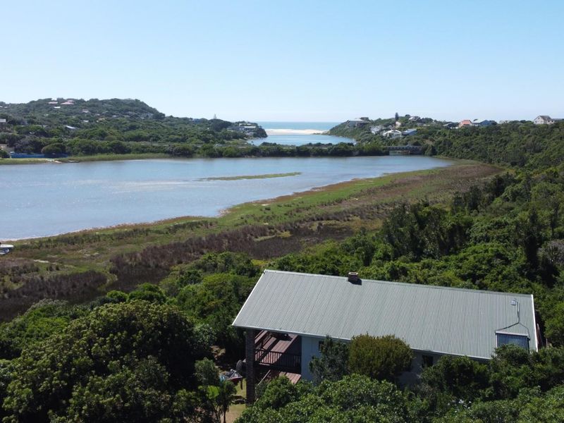 Aerial view of a residential property nestled in lush greenery, featuring a scenic outlook over the nearby lagoon and coastal landscape.