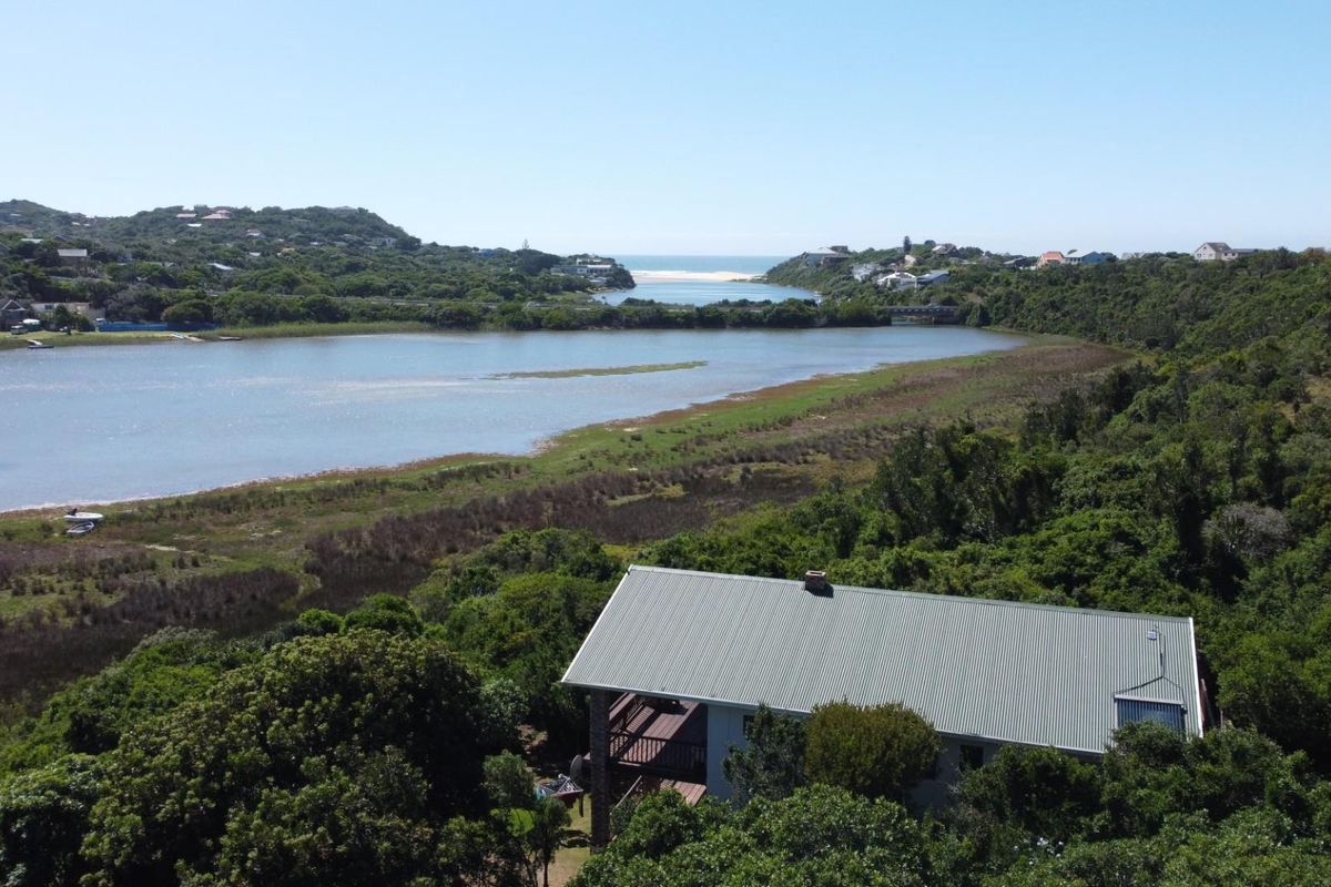 Aerial view of a residential property nestled in lush greenery, featuring a scenic outlook over the nearby lagoon and coastal landscape.
