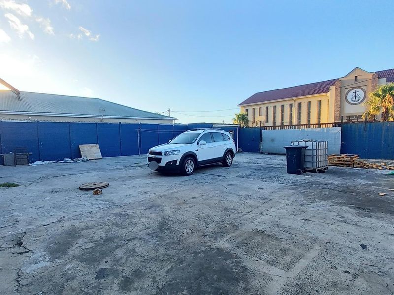 A large, paved rear yard area featuring perimeter fencing and concrete surfacing, providing ample open space.