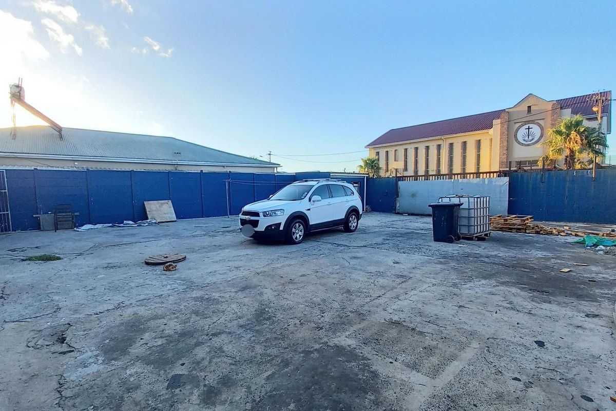 A large, paved rear yard area featuring perimeter fencing and concrete surfacing, providing ample open space.