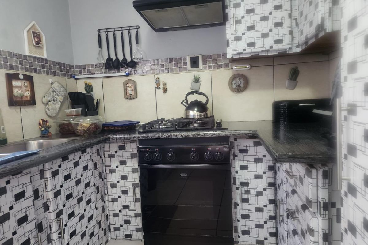 A functional kitchen featuring dark granite countertops, a built-in gas stove with extractor fan, and patterned cabinetry.