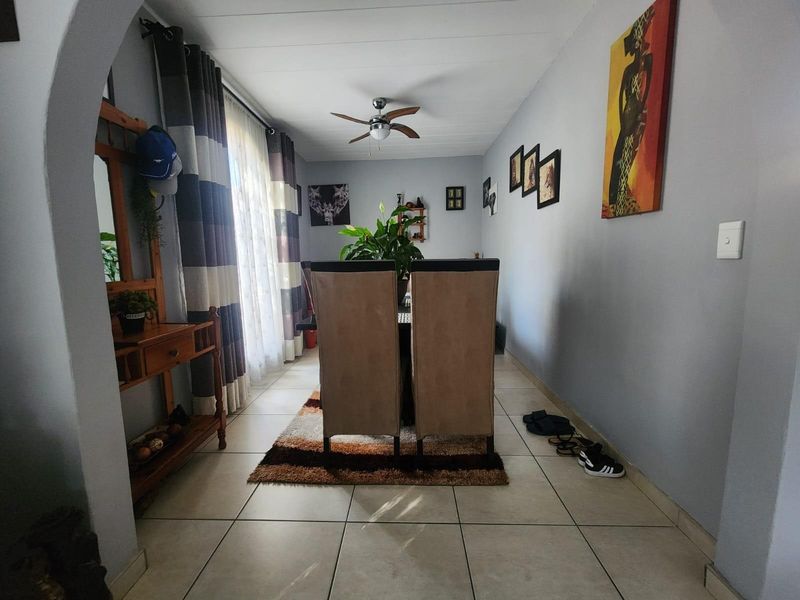 A dining area featuring tiled flooring, a ceiling fan, and a large window with curtains, providing a functional space for meals.