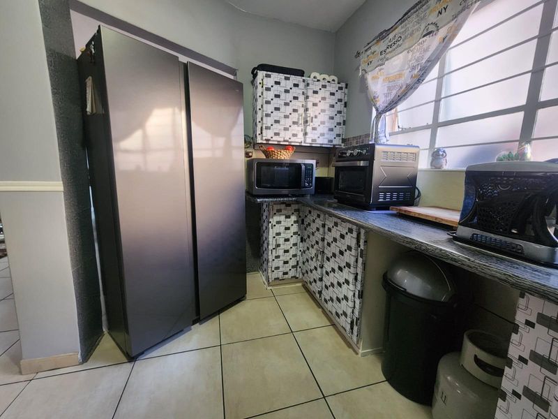 A compact kitchen area featuring tiled flooring, laminate countertops, and built-in cabinetry with a patterned finish.