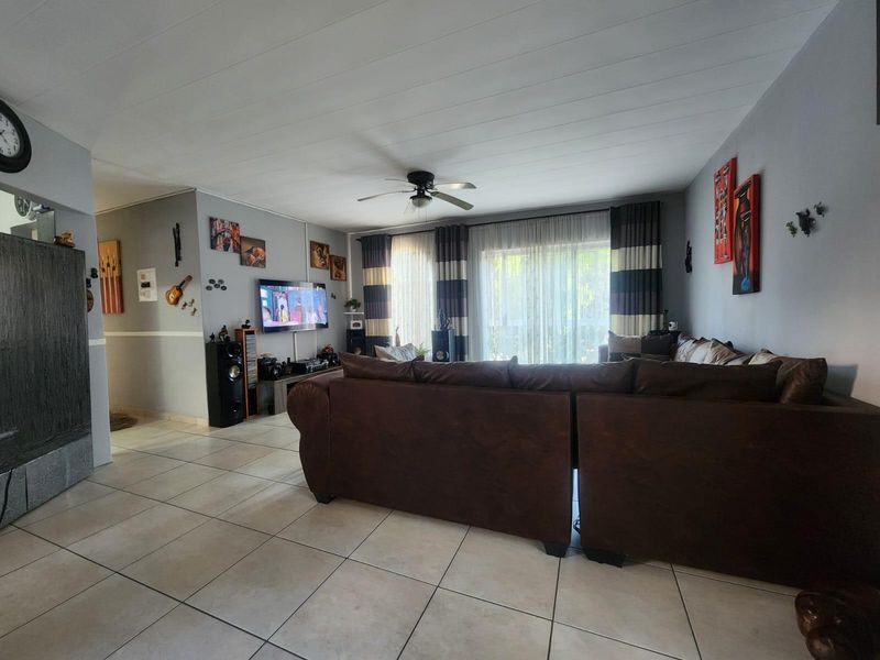 Spacious living room featuring tiled flooring, a ceiling fan, and large sliding glass doors providing access to the exterior.