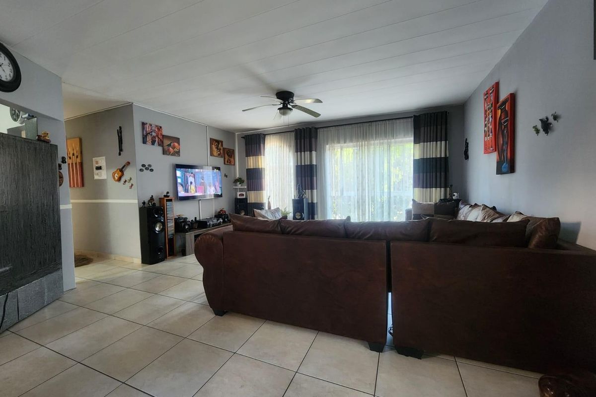 Spacious living room featuring tiled flooring, a ceiling fan, and large sliding glass doors providing access to the exterior.