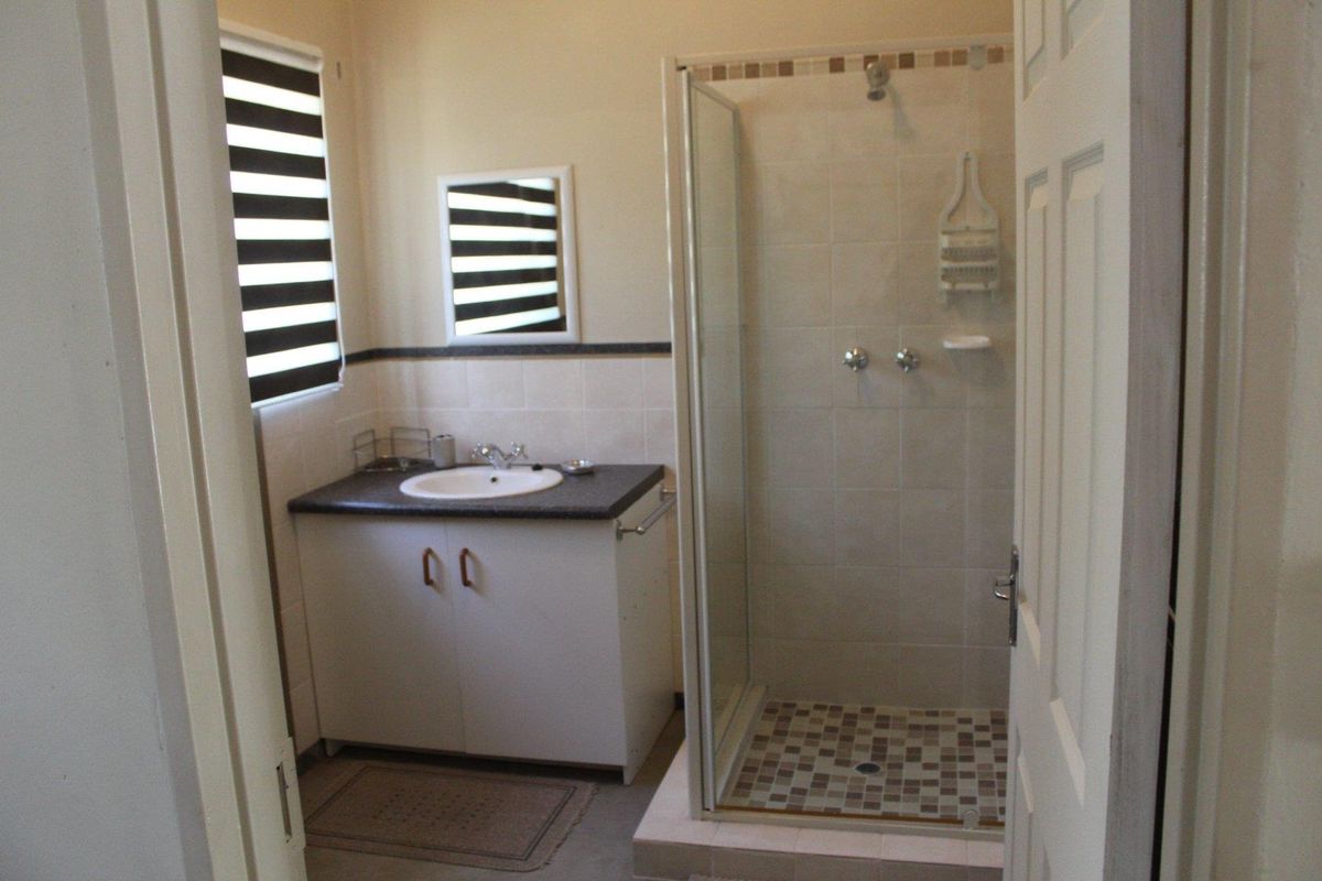 A functional bathroom featuring a glass-enclosed shower, a vanity with a basin, and tiled finishes.