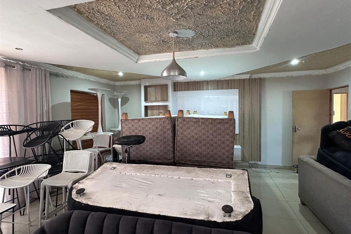 Spacious living area featuring a decorative recessed ceiling with pendant lighting and built-in wall cabinetry, offering a versatile layout for interior design.