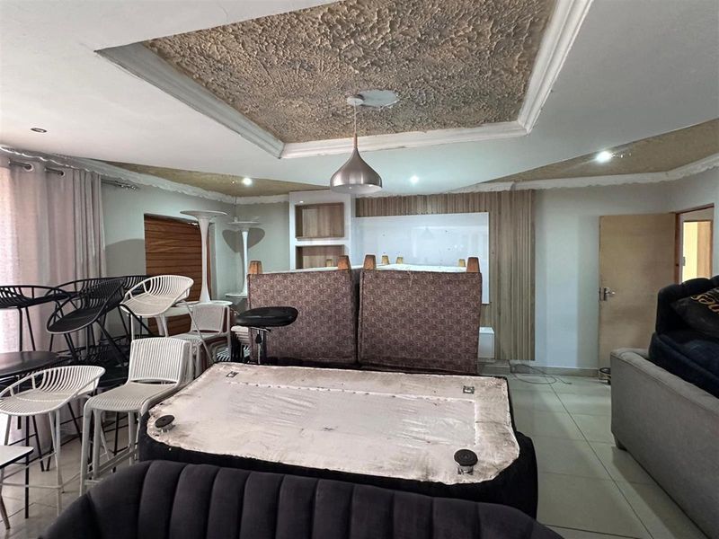Spacious living area featuring a decorative recessed ceiling with pendant lighting and built-in wall cabinetry, offering a versatile layout for interior design.
