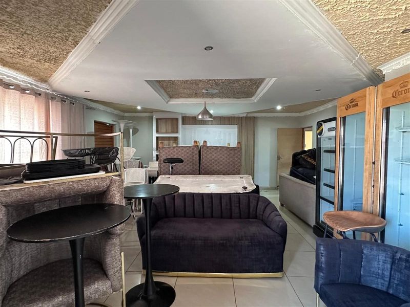 Spacious open-plan living area featuring tiled flooring and a distinctive textured ceiling with recessed lighting.
