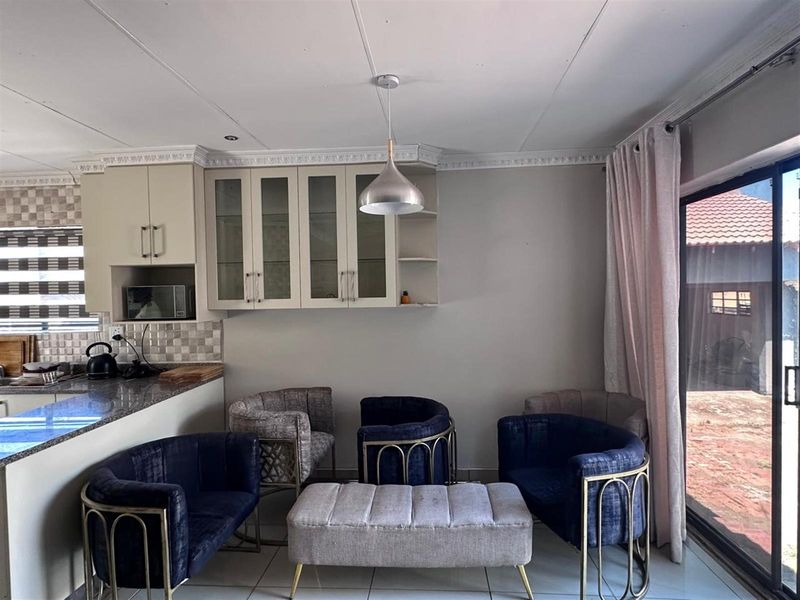 Open plan kitchen and living area featuring tiled flooring, built-in cabinetry, granite countertops, and sliding glass doors leading to the exterior.
