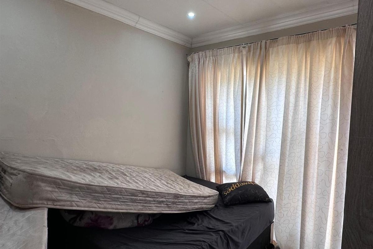 A bedroom featuring neutral wall finishes, crown molding, and floor-to-ceiling curtains covering the window.