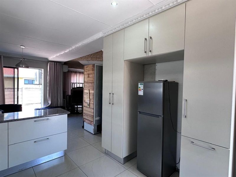 Open plan kitchen area featuring built-in cabinetry, granite countertop, and tiled flooring, seamlessly connecting to the adjacent living space.