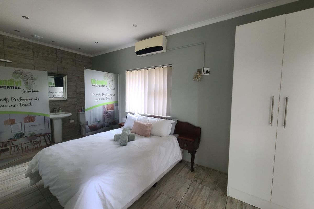 A bedroom featuring tiled flooring, a built-in wardrobe, an air conditioning unit, and an integrated bathroom vanity area.