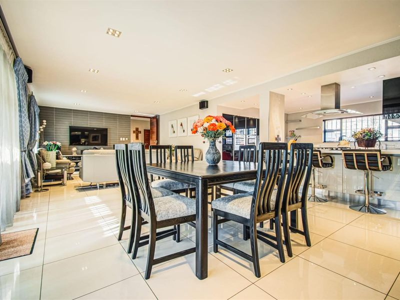 Spacious open-plan living, dining, and kitchen area featuring polished porcelain tiles, modern cabinetry, and a central kitchen island with breakfast bar seating.