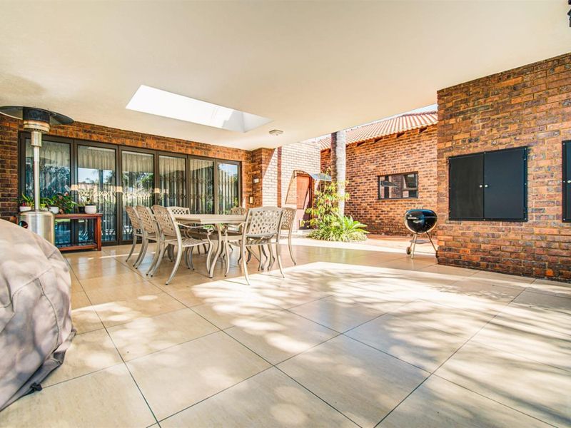 Spacious covered patio featuring tiled flooring, a built-in braai, and a skylight, seamlessly connecting to the interior through large stacking doors.