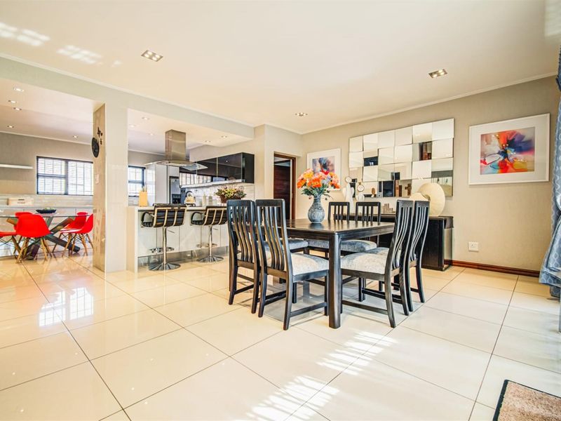Spacious open-plan living and dining area featuring polished porcelain tiles, recessed lighting, and a modern kitchen with a central island and breakfast bar.
