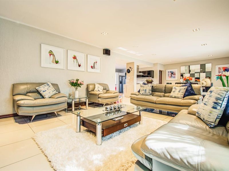 Spacious open-plan living area featuring neutral tiled flooring and recessed downlighting, seamlessly connecting to the kitchen and dining space.