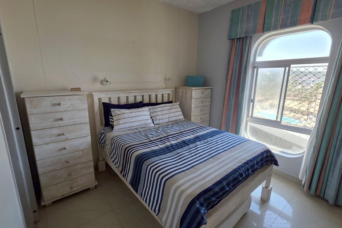 A bedroom featuring tiled flooring, a large arched window with security mesh, and neutral wall finishes.