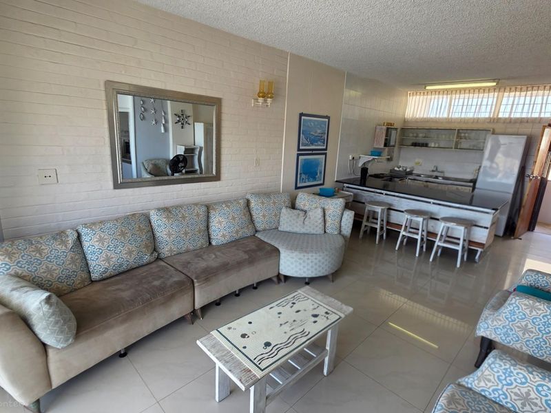 Open-plan living and kitchen area featuring a breakfast bar, tiled flooring, and a textured brick feature wall.