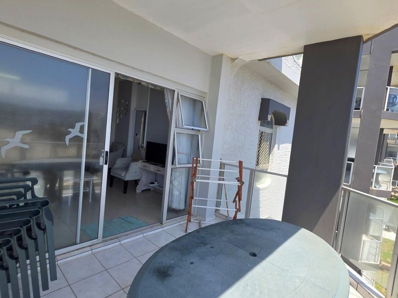 A covered balcony featuring tiled flooring and glass balustrades, providing an outdoor extension to the interior living space.