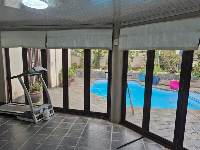 Indoor living space featuring large folding glass doors opening directly onto a paved patio and swimming pool area.