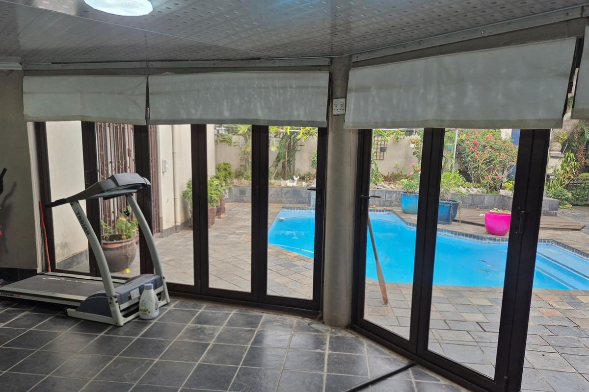 Indoor living space featuring large folding glass doors opening directly onto a paved patio and swimming pool area.