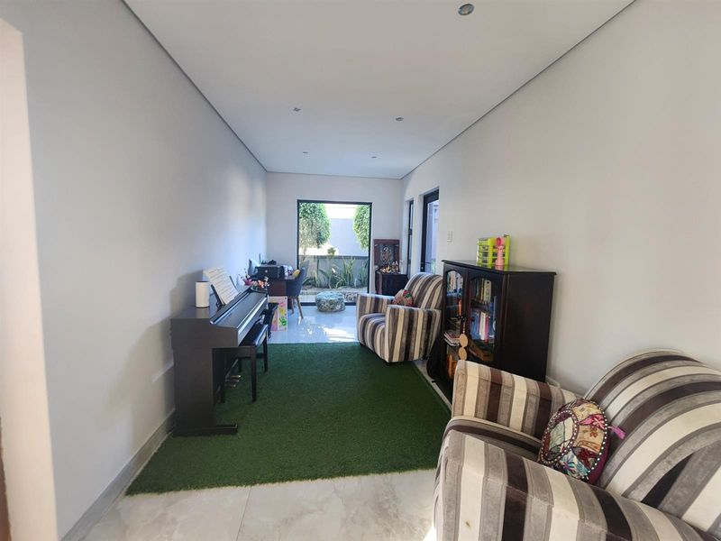 A bright living area featuring tiled flooring, recessed downlighting, and large sliding glass doors providing direct access to the outdoor space.