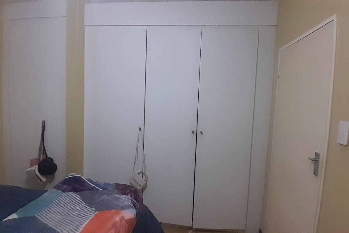 A bedroom featuring built-in cupboards with white doors and a standard interior door.