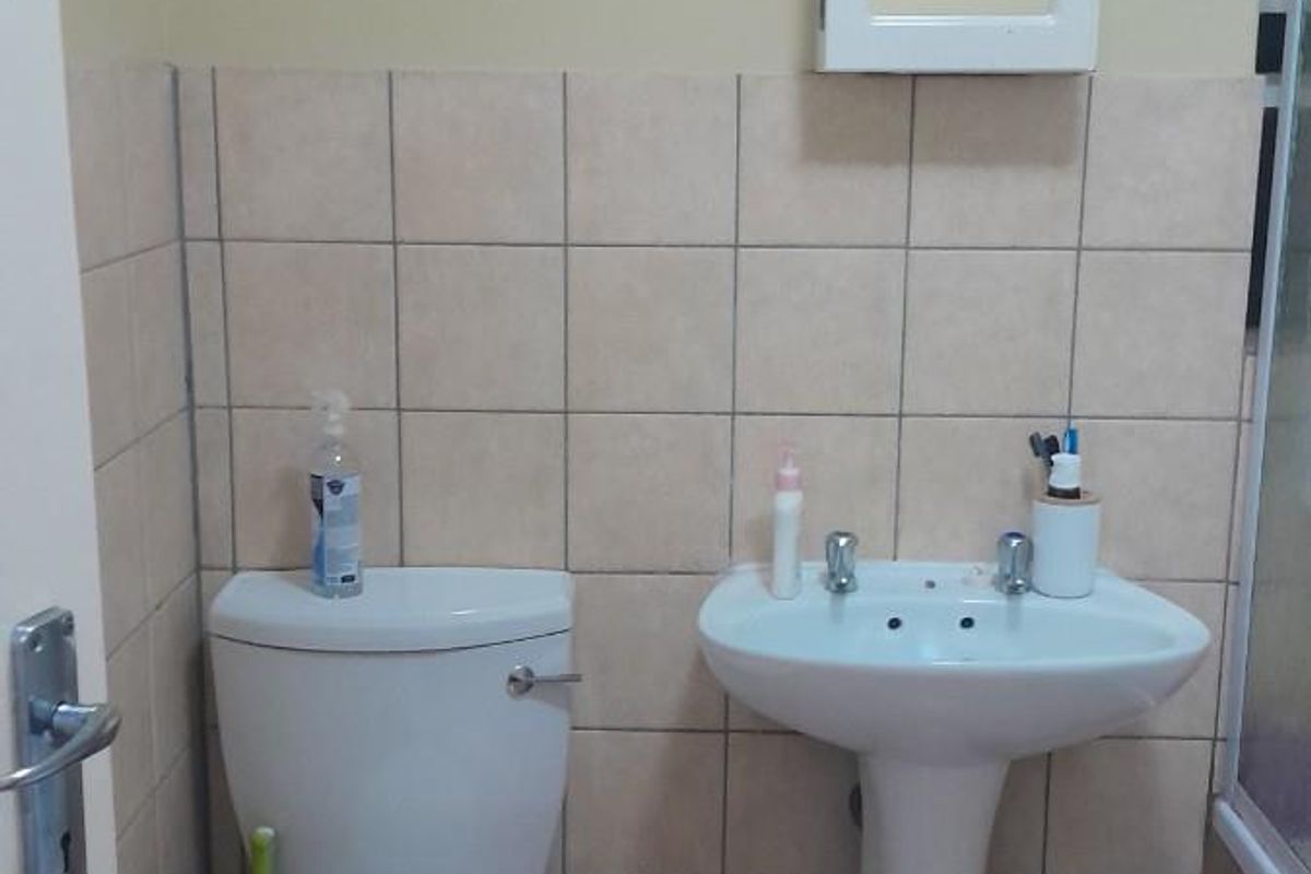 A functional bathroom featuring a pedestal basin, a standard toilet, and a wall-mounted medicine cabinet with tiled splashbacks.